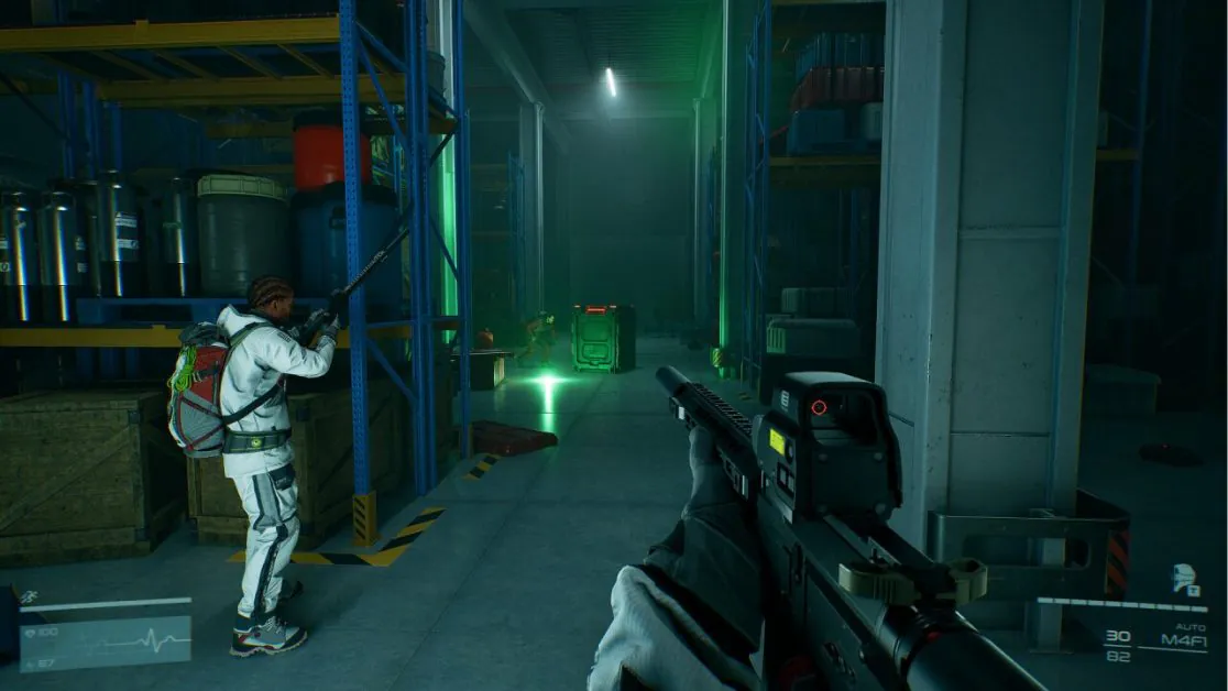 Armed players explore a dimly lit industrial warehouse with crates