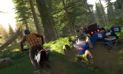 Un pilote de moto tout-terrain court aux côtés d'un buggy tout-terrain à travers une forêt dense dans un jeu PS Plus