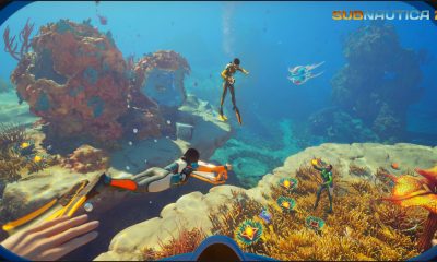 Three divers swim through vibrant coral habitats in Game Pass crossplay game