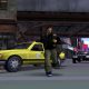 PS2 game scene showing a man running past yellow taxi and police car