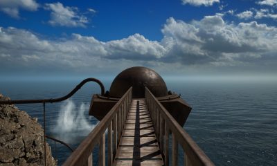 A narrow wooden bridge leads toward a domed building above the sea in Riven.