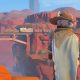 A builder in a broad-brimmed hat looks across the desert landscape near Sandrock.