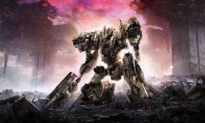 An armored combat mech stands amid ruined structures beneath a red and gray sky in Armored Core VI artwork.