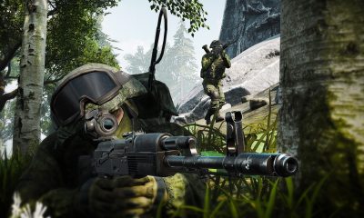 A soldier wearing a gas mask and helmet aims a rifle in a wooded setting.