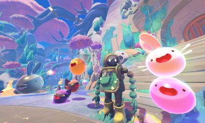 Colorful slimes leap through a bright landscape in Slime Rancher 2.