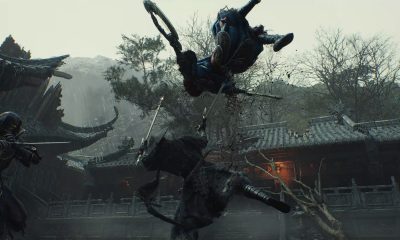 Warriors clash with swords in a rain-soaked courtyard surrounded by tiled roofs in Phantom Blade Zero.