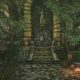 Stone steps leading to an overgrown ruined entrance beside a campfire in Queen’s Domain.