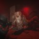 The Traveler confronts a creature in a red-lit room in Cronos: The New Dawn.